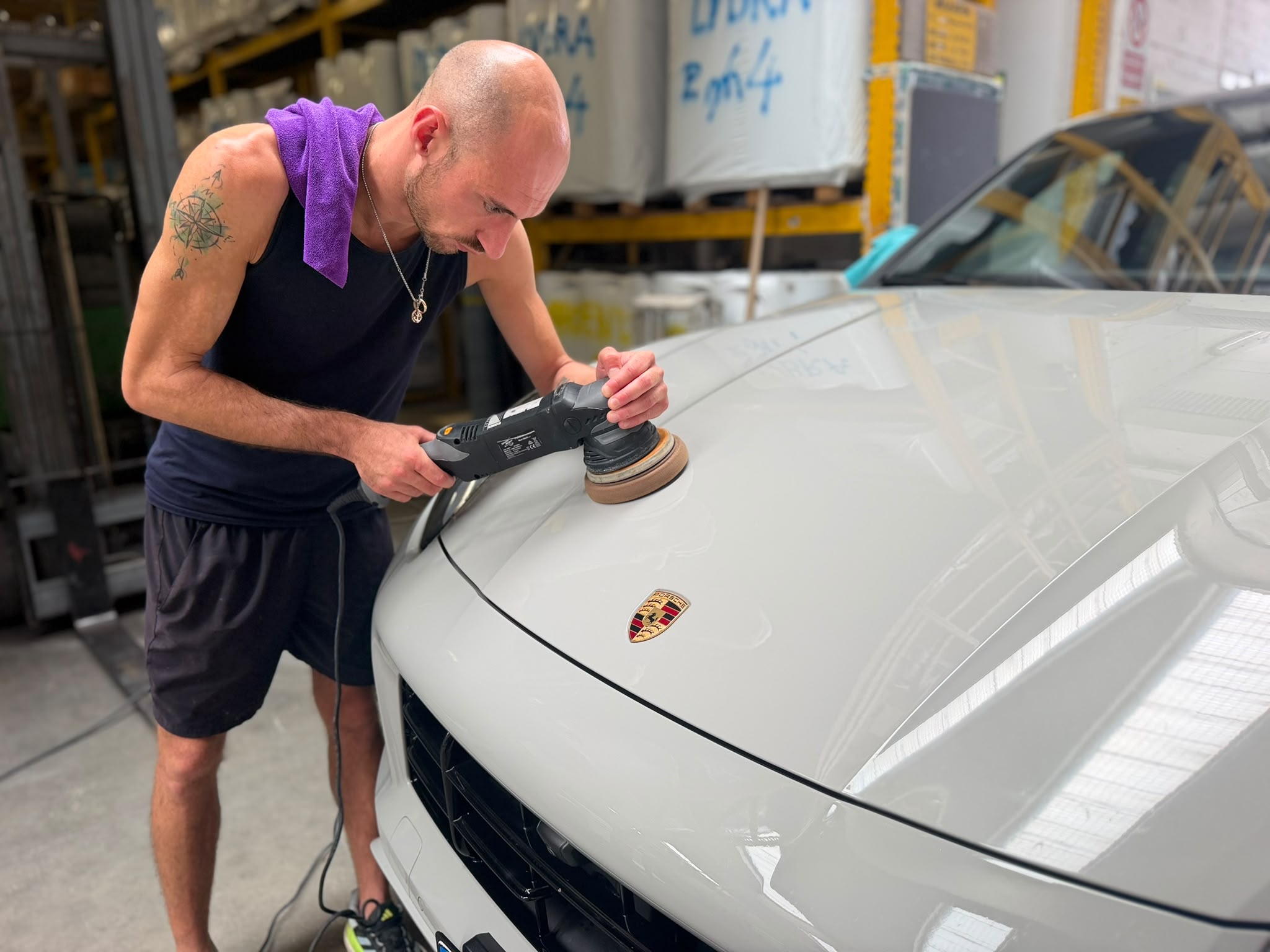 Massimiliano Baldo mentre lucida il cofano di una Porsche grigia con la lucidatrice orbitale